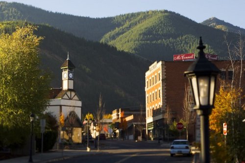 A scenic view of a small town with mountains in the background, featuring a clock tower and historic buildings.
