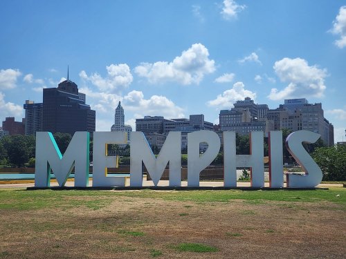 Large "MEMPHIS" sign in a park with a city skyline and blue sky in the background.