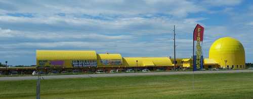 A large yellow building with a dome, labeled "Fireworks," set against a cloudy sky and green grass.