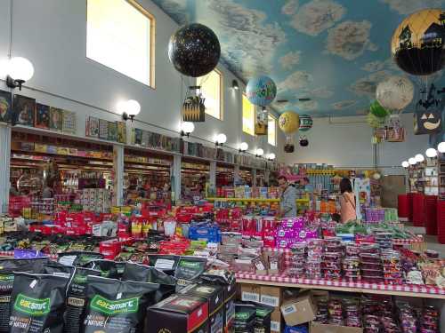 A colorful candy store filled with various sweets, snacks, and decorative hot air balloons hanging from the ceiling.