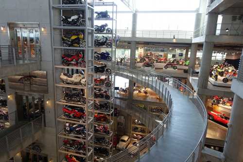 A modern motorcycle museum featuring multiple levels of displayed bikes and a spiral walkway.