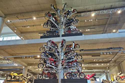 A unique display of motorcycles arranged in a tree-like structure inside a modern showroom.