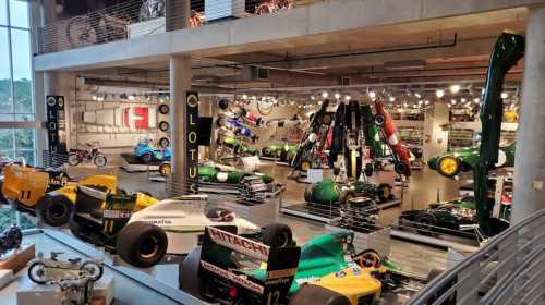 A spacious automotive museum featuring various vintage race cars and motorcycles on display.