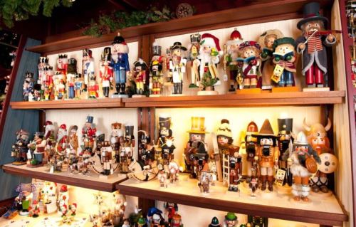 A display of colorful nutcracker figurines arranged on wooden shelves, featuring various characters and designs.