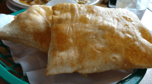 Two golden-brown, flaky pastries served in a green basket on a white napkin.
