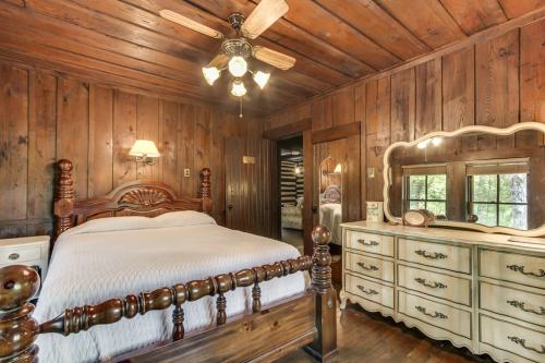 Cozy bedroom with wooden walls, a ceiling fan, a bed with a carved headboard, and a vintage dresser.
