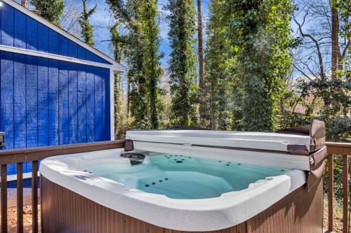 A hot tub on a wooden deck surrounded by trees and a blue shed in the background.