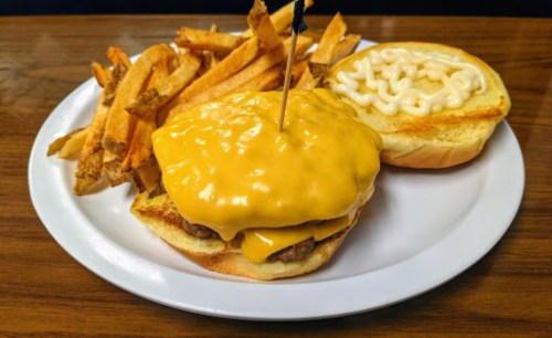 A cheeseburger with melted cheese and a side of crispy French fries on a white plate.