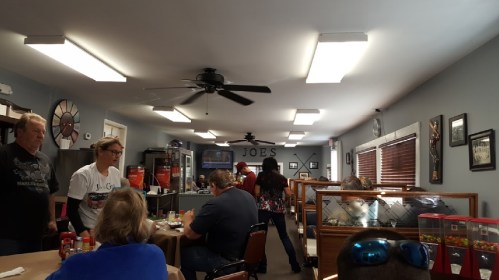 A cozy diner interior with patrons eating, staff serving, and decor on the walls, creating a welcoming atmosphere.