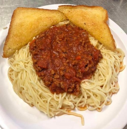 A plate of spaghetti topped with meat sauce, flanked by two slices of toasted bread.