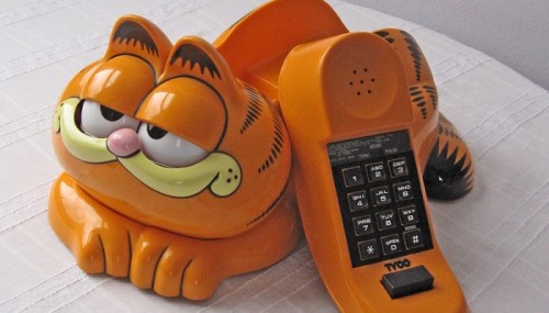 A Garfield-themed telephone with a bright orange design, featuring a cartoon cat lying beside the keypad.