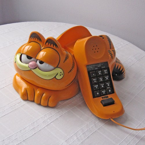 A Garfield-themed telephone resting on a table, featuring a playful cat design in orange and black.