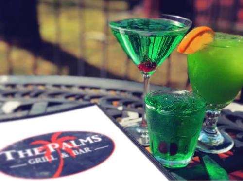 Three vibrant green cocktails on a table, with a menu from The Palms Grill & Bar in the foreground.