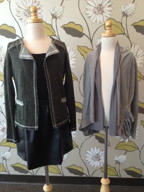 Two mannequins display a stylish outfit: a green jacket with embellishments and a gray draped shawl over a black top.