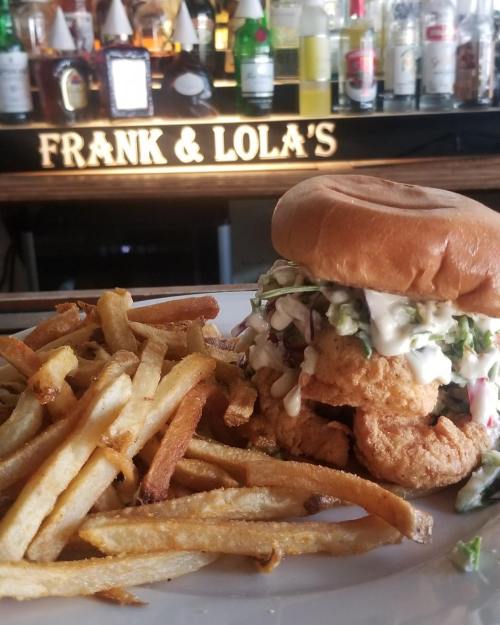 A crispy chicken sandwich with coleslaw and mayonnaise, served with a side of golden French fries.