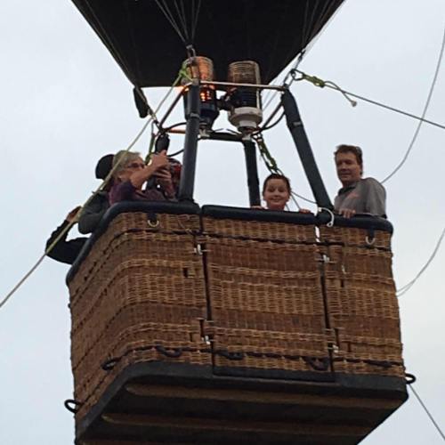 A group of four people in a hot air balloon basket, enjoying a scenic view from above.