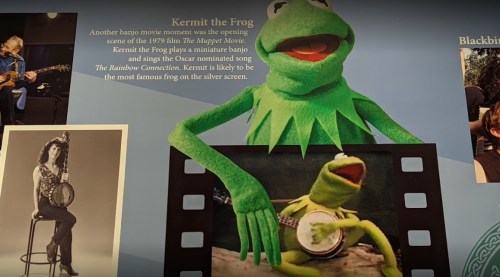 Kermit the Frog plays a banjo, featured in a display about his role in "The Muppet Movie" and "The Rainbow Connection."