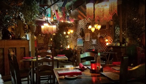 Cozy restaurant interior with wooden tables, warm lighting, and decorative plants, creating an inviting atmosphere.