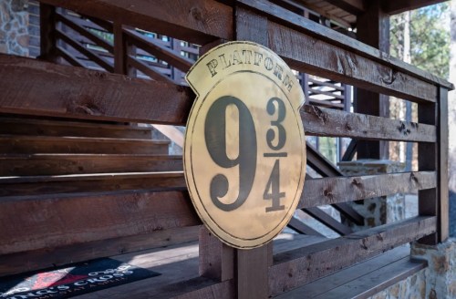 A brass sign reading "Platform 9¾" mounted on wooden stairs in a rustic setting.