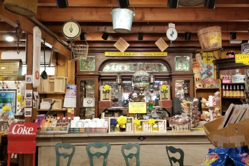 A cozy gift shop interior with vintage decor, a wooden counter, and various items displayed on shelves and walls.