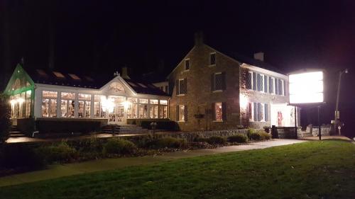 A stone building at night, featuring illuminated windows and a large sign, surrounded by greenery.