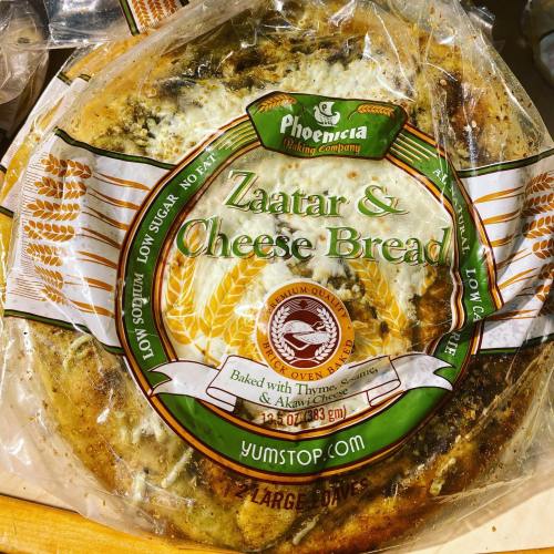 A package of Zaatar & Cheese Bread from Phoenicia Baking Company, featuring herbs and cheese on a round loaf.