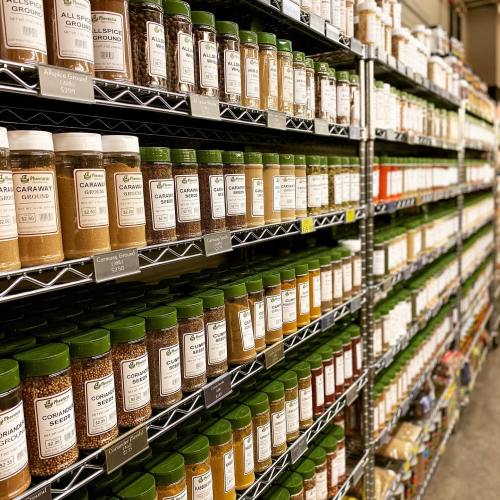 A well-organized shelf filled with various spice jars, labeled and neatly arranged in rows.