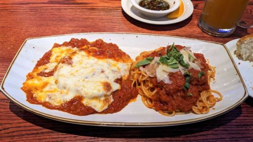 A plate of pasta with marinara sauce, topped with cheese and herbs, alongside spaghetti in a rich tomato sauce.