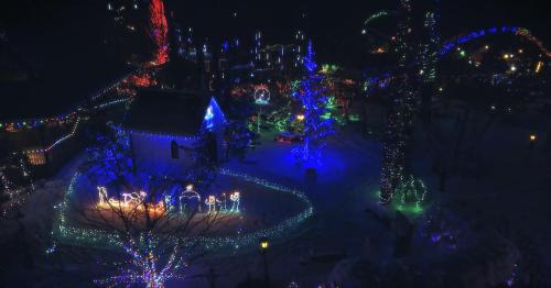 A festive scene featuring colorful Christmas lights illuminating a snowy landscape with trees and decorations.
