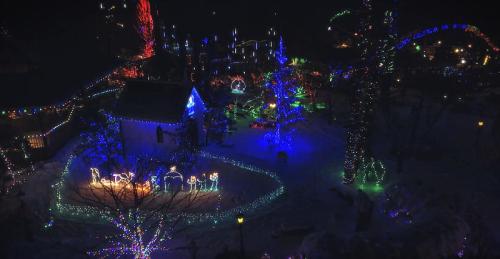 Aerial view of a festive display with colorful Christmas lights illuminating trees and decorations in a snowy landscape.