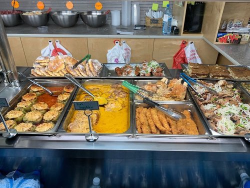 A buffet display featuring various dishes, including fried items, casseroles, and salads in metal trays.
