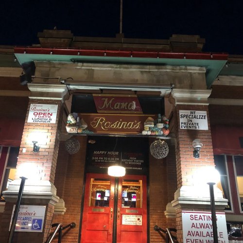 The entrance of Rosina's restaurant at night, featuring bright lights and signs for happy hour and private events.
