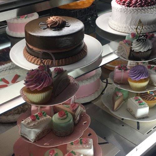 A display of assorted cakes and pastries, including a chocolate cake, cupcakes, and decorated mini desserts.