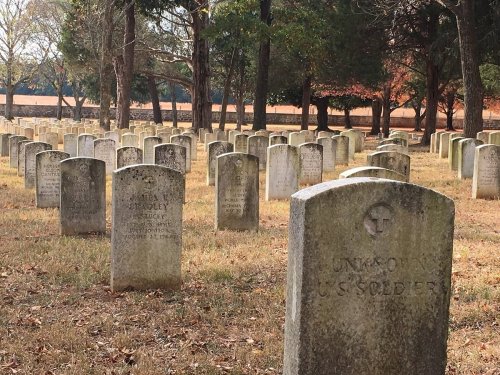 A cemetery with rows of gravestones, including one marked "Unknown U.S. Soldiers," surrounded by trees.