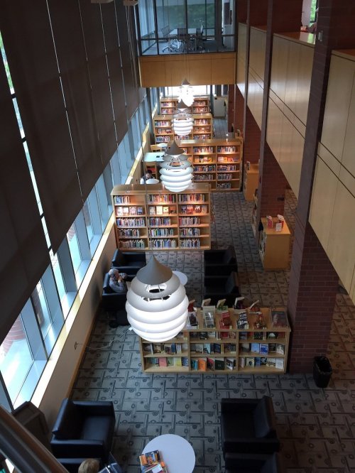 A spacious library interior with bookshelves, modern lighting, and seating areas for reading and studying.