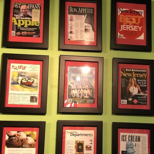 A collage of framed magazine covers on a green wall, featuring food, travel, and lifestyle themes.