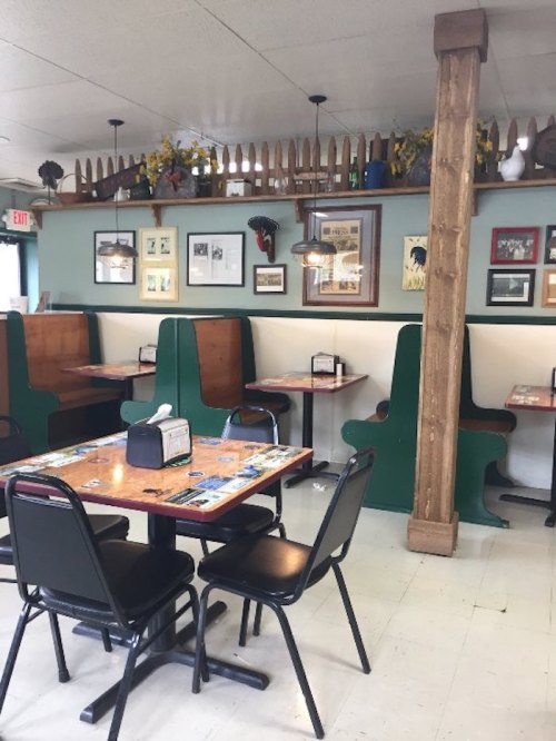 Cozy diner interior with green booths, wooden tables, and framed pictures on the walls. Bright and inviting atmosphere.