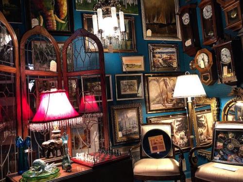 A cozy room filled with vintage decor, including clocks, paintings, and lamps, creating an eclectic atmosphere.
