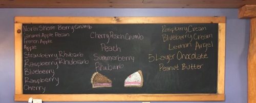 Chalkboard menu listing various pie flavors and desserts, including berry, peach, and peanut butter options.