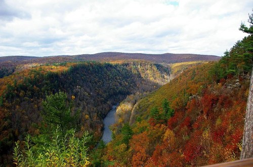 A scenic view of a river winding through a colorful autumn landscape with hills and trees.