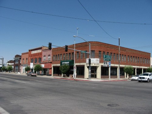 A street view of historic brick buildings with shops, traffic lights, and clear blue skies.