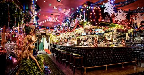 A festive bar decorated with colorful lights, ornaments, and holiday decorations, creating a cheerful atmosphere.