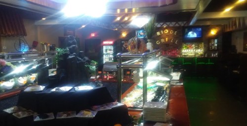 A buffet setup in a restaurant featuring various dishes, a decorative waterfall, and a bar area in the background.