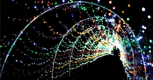 A colorful tunnel of twinkling lights in various hues against a dark background.