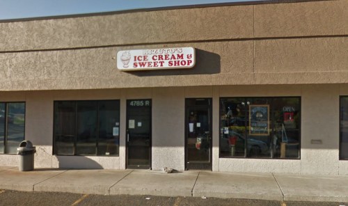 Exterior of Rizzuto's Ice Cream & Sweet Shop, featuring a sign and large windows, with a trash can nearby.