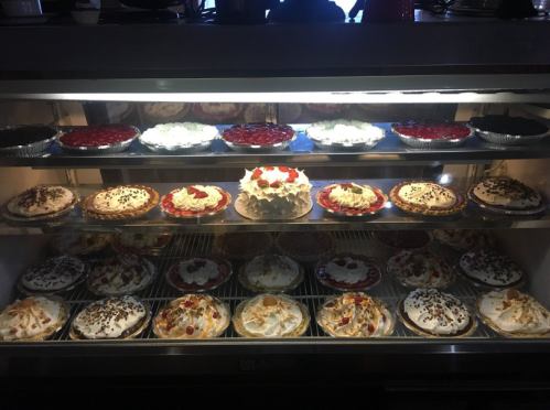 A display case filled with various colorful pies, including fruit, cream, and chocolate varieties.