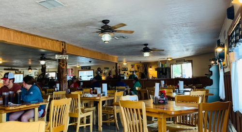 A cozy restaurant interior with wooden tables, ceiling fans, and patrons enjoying their meals.
