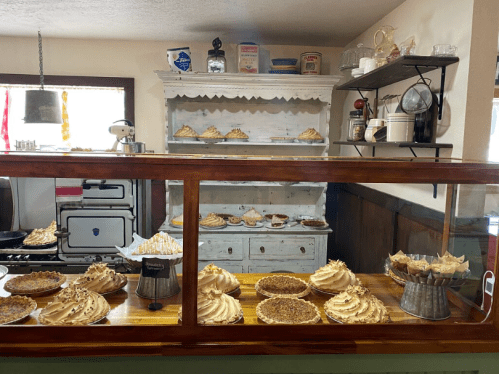 A cozy bakery display featuring various pies with meringue toppings, set in a charming kitchen environment.