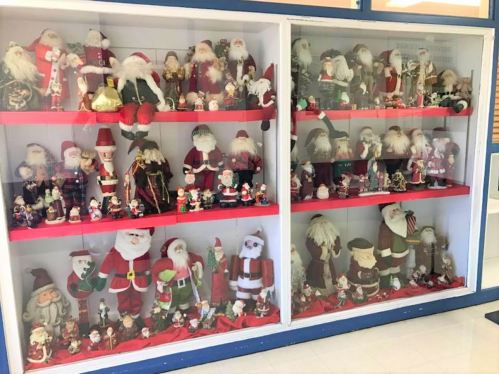 A display case filled with various Santa Claus figurines and decorations in different styles and sizes.