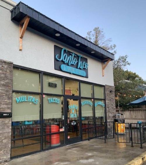 Exterior of Santo Taco Taqueria, featuring large windows and a sign with the restaurant's name and menu items.
